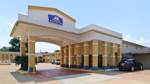 The entrance of the Americas Best Value Inn with a clear sky and a parking area in front.