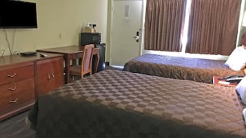 A hotel room with two beds, a desk, a chair, a television, and a door.