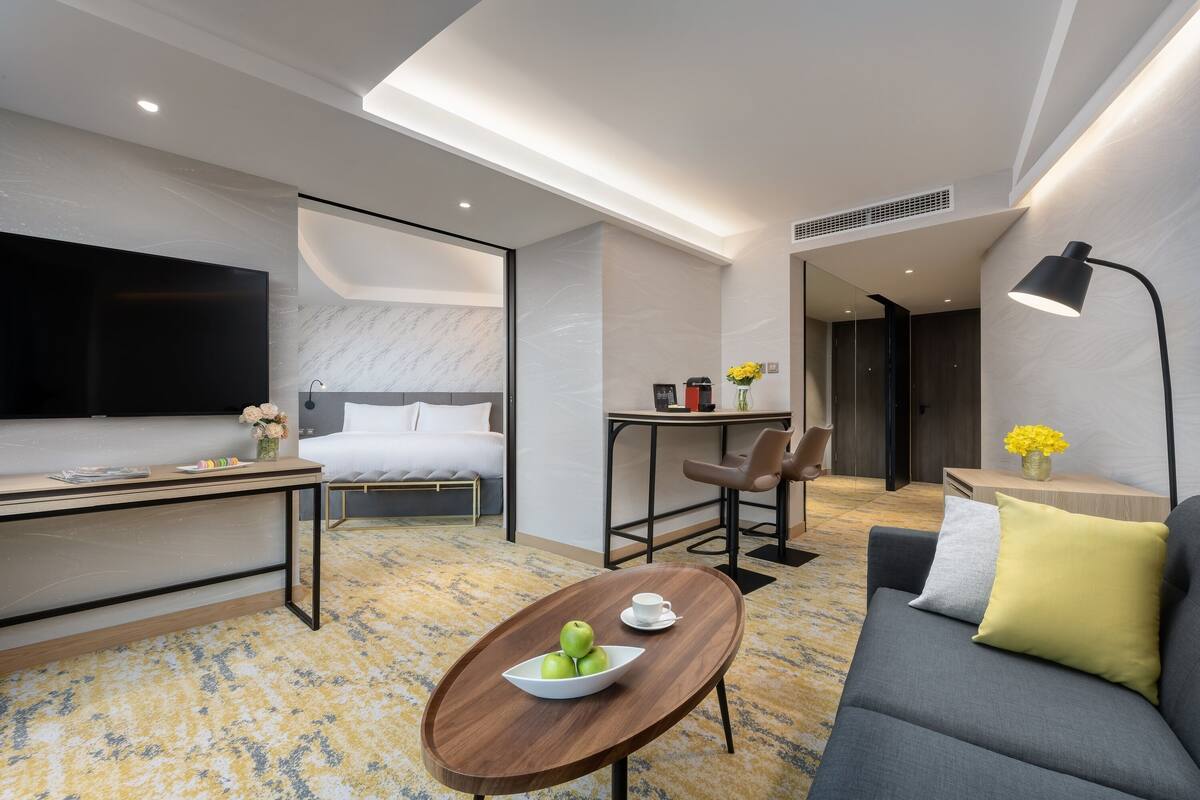 A modern hotel room with a bed, a desk, a sofa, and a coffee table.