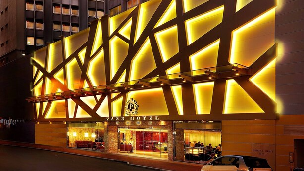 Un hotel con fachada moderna, varios pisos y ventanas iluminadas.