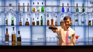 Una zona de bar con estantes llenos de botellas de licor y vasos.