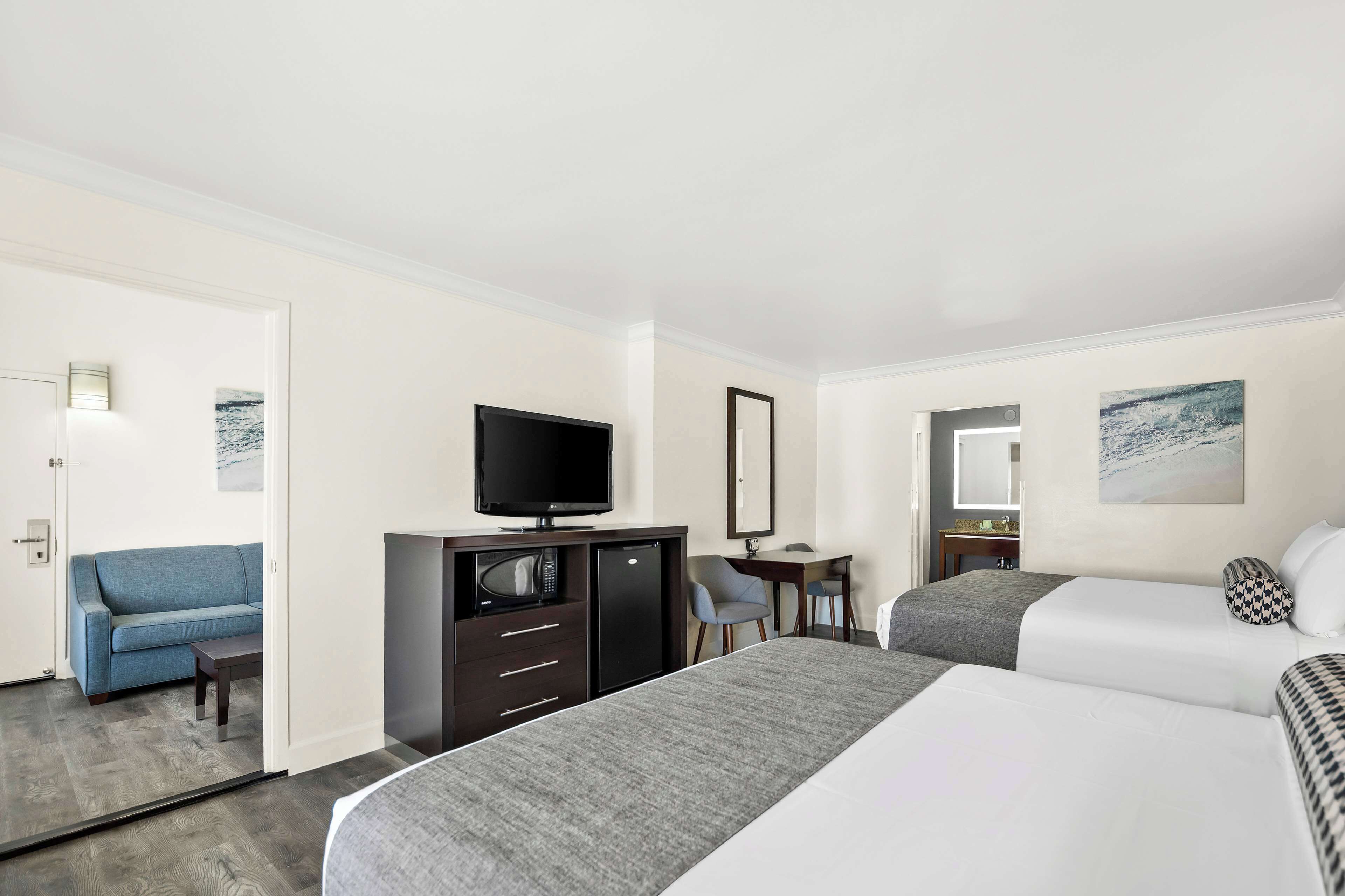Een hotelkamer met twee bedden, een bureau, een televisie en een bank.