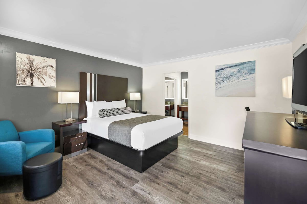 A modern hotel room with a bed, a desk, a chair, and a small table.