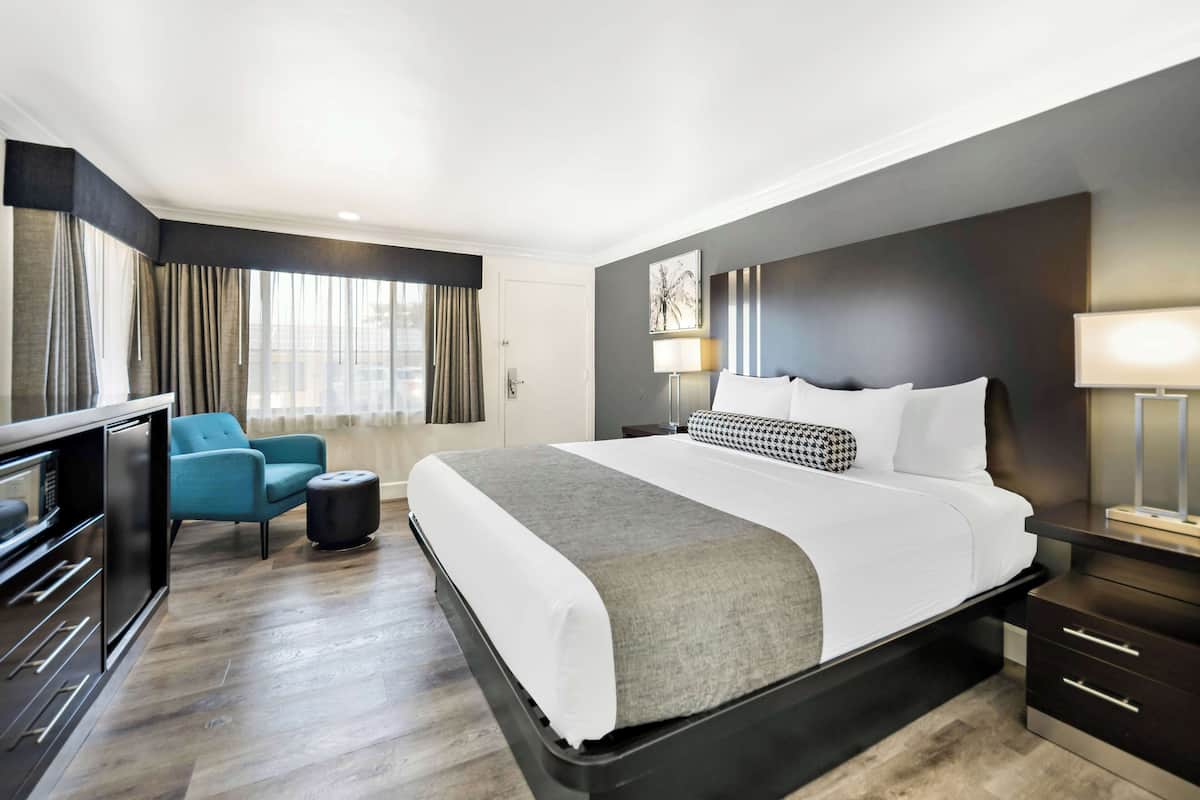 A hotel room with a large bed, a desk, a chair, and a TV.