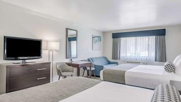 A hotel room with two beds, a desk, a chair, a television, and a window with curtains.