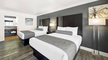 A hotel room with two beds, a nightstand, a lamp, and a painting on the wall.