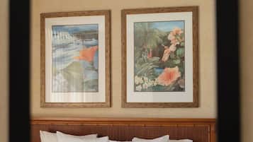 Habitació d'hotel amb un llit, dos quadres al mur i un panell de llit de fusta.