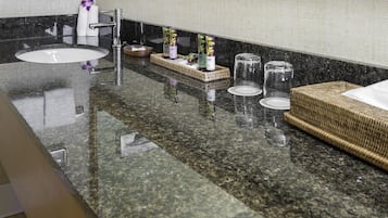 A bathroom with a granite countertop, a sink, a mirror, and a towel rack.