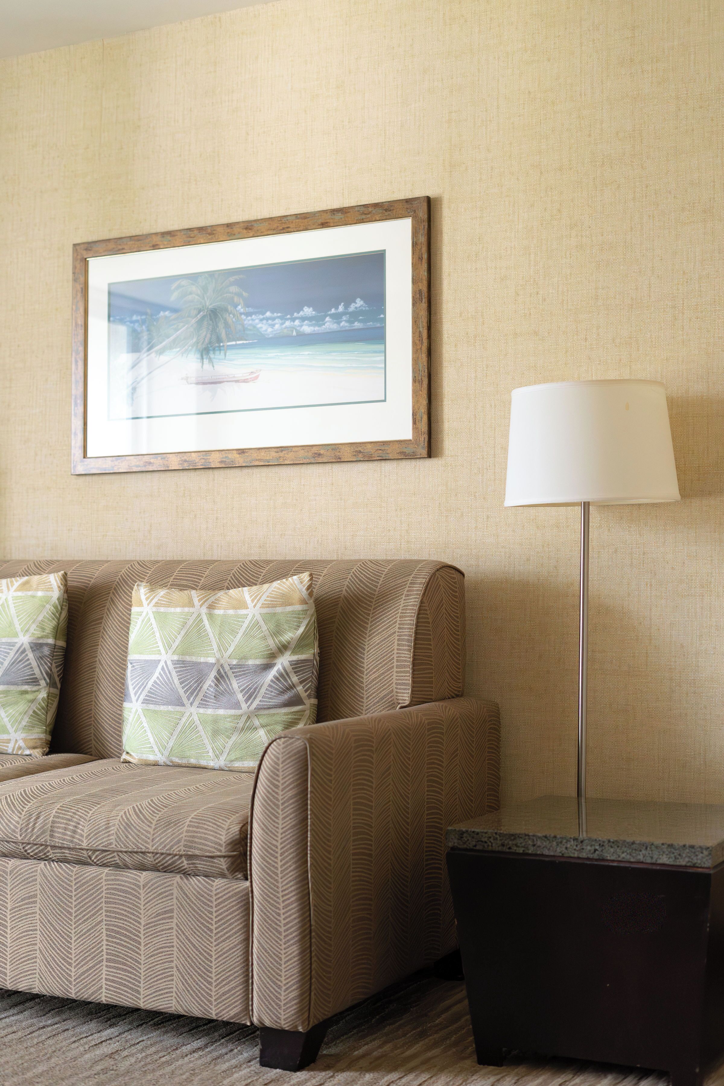 A room with a sofa, a framed picture, a floor lamp, and a small table.