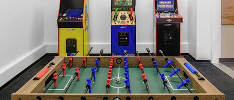 A foosball table with three arcade machines beside it.