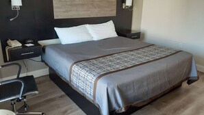 Una habitación de hotel con cama, mesitas de noche, un escritorio con silla y teléfono.