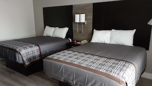 Habitación de hotel con dos camas, una mesita de noche, un teléfono y una lámpara fijada a la pared.