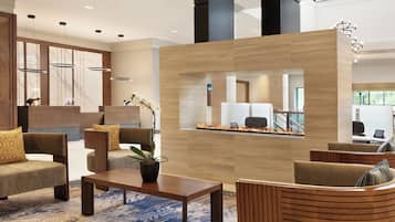 A modern lobby with seating areas, a reception desk, and a view of the interior.