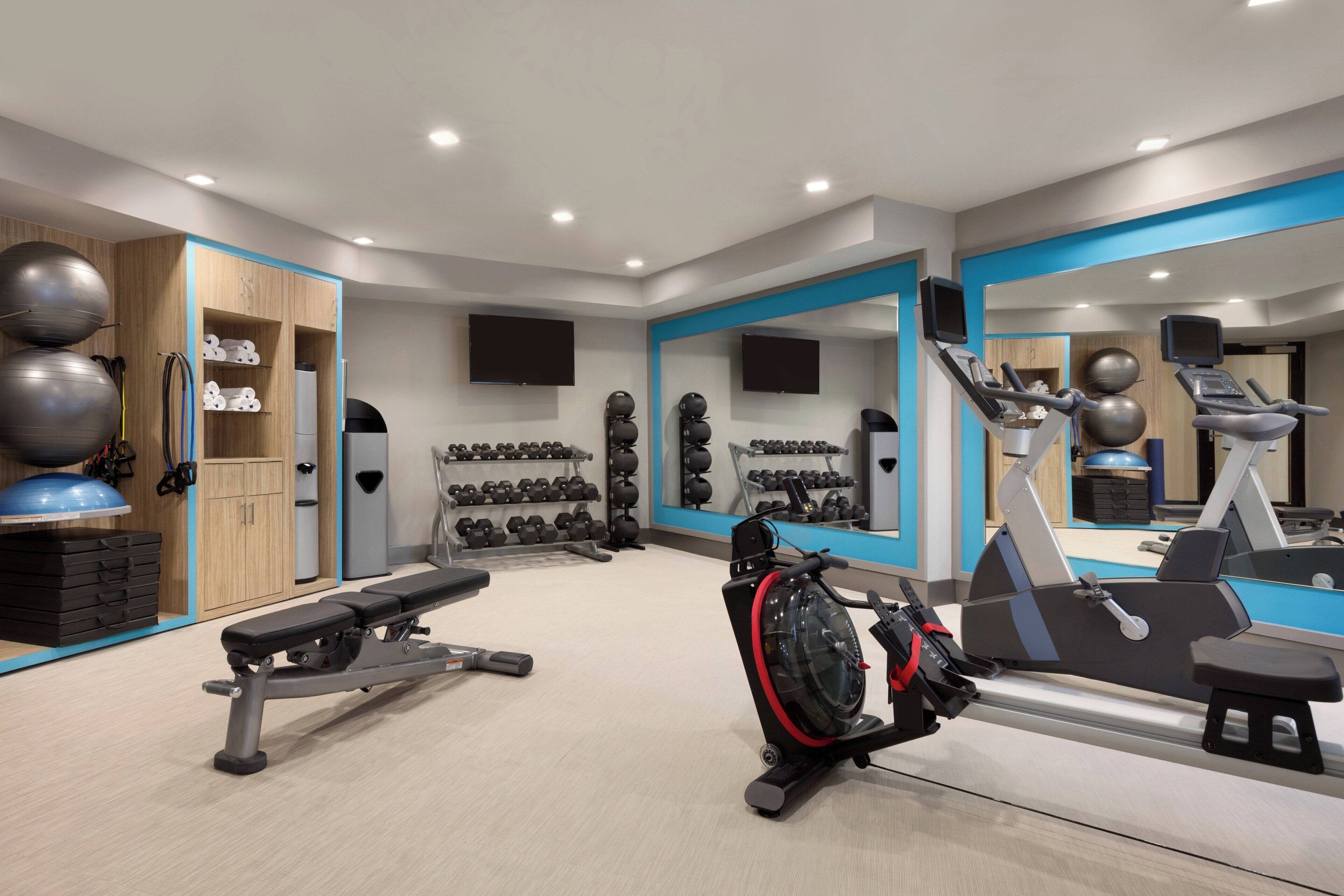 A well-equipped home gym with exercise equipment, a bench, and a mirror.