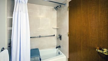 Un baño con bañera, ducha y puerta de madera.