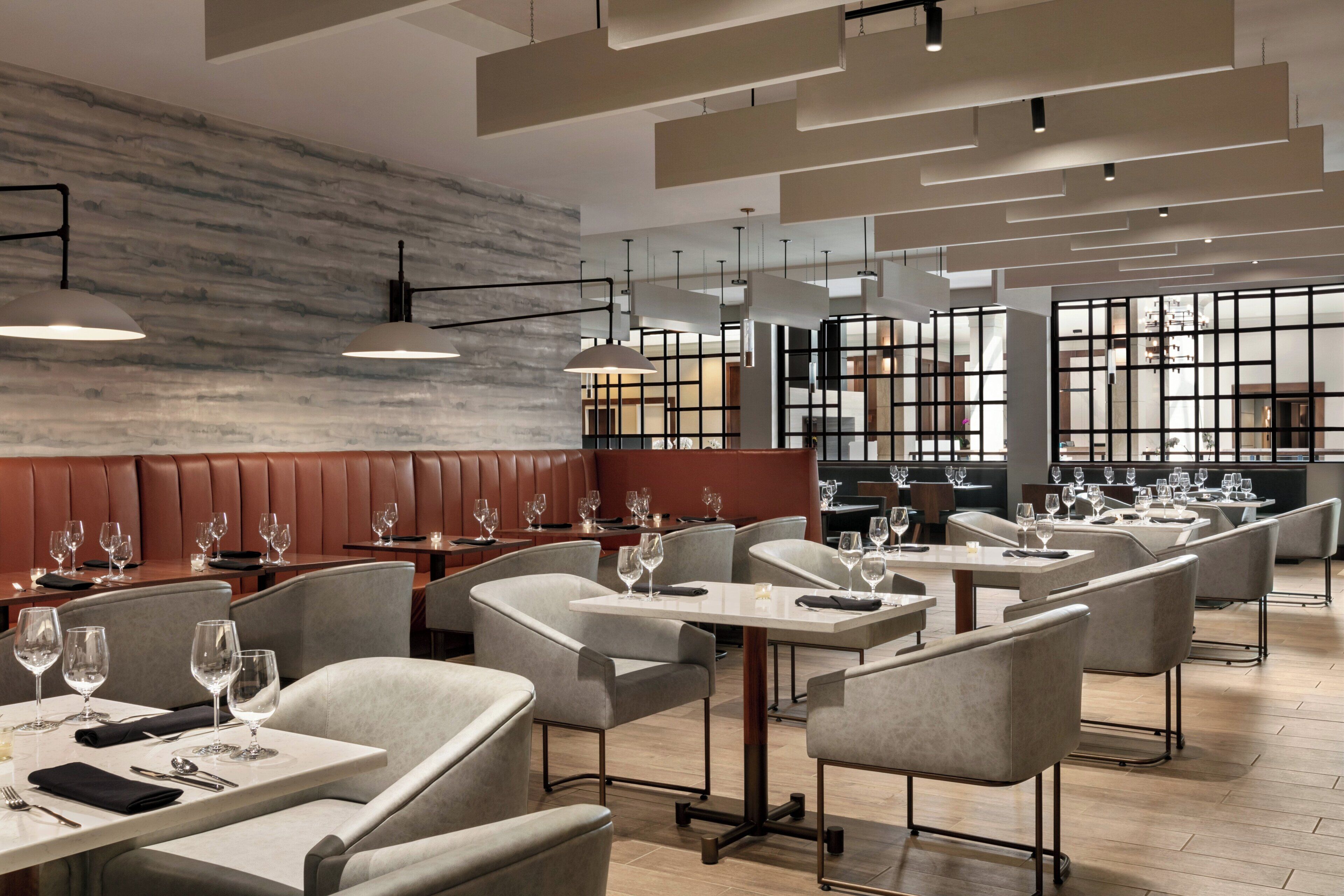 A modern restaurant interior with booths, tables, and hanging pendant lights.