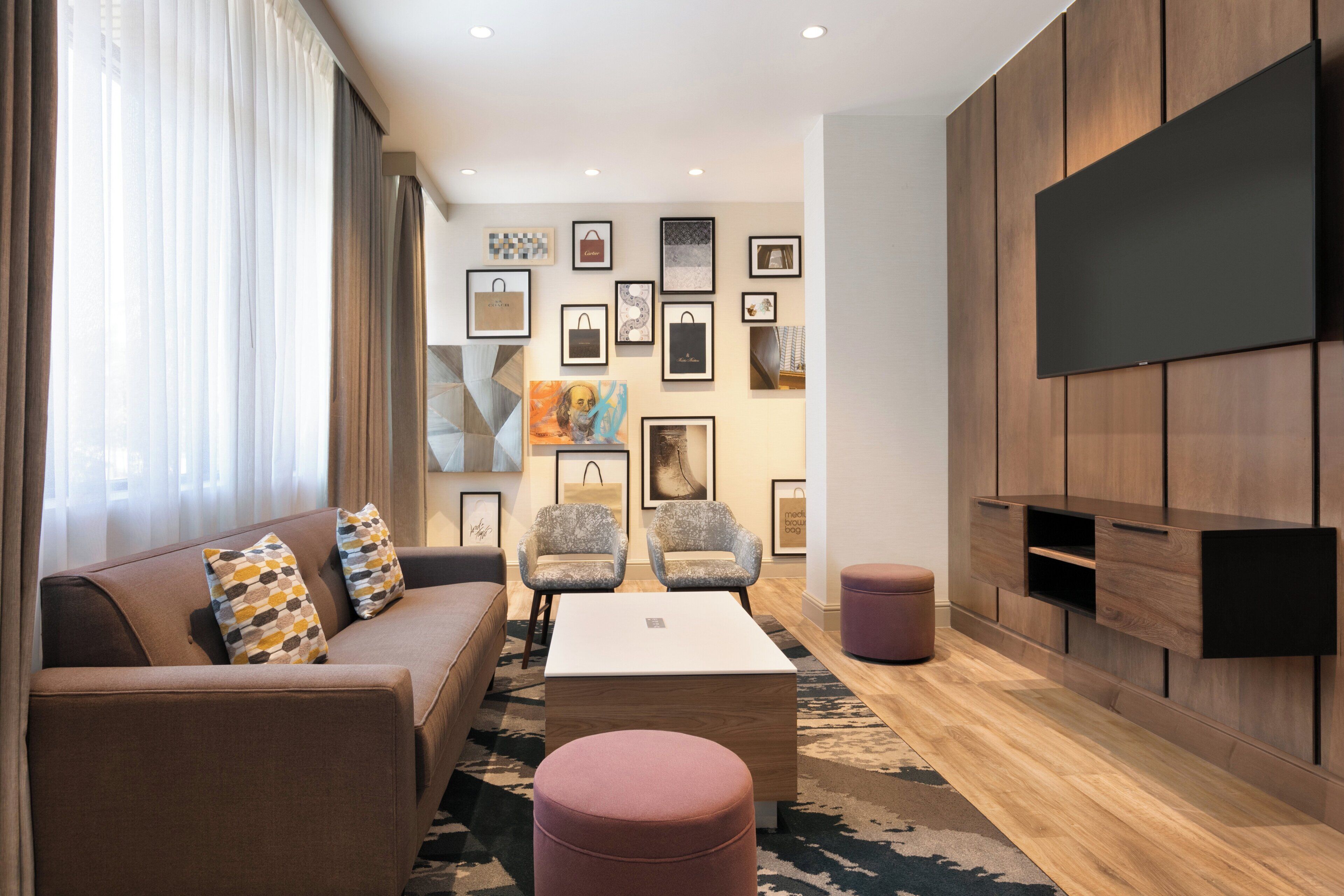 Una sala de estar moderna con un sofá, sillones, una mesa de centro y un televisor montado en la pared.