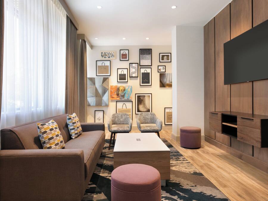 Ein modernes Wohnzimmer mit einer Couch, Sesseln, einem Couchtisch und einem an der Wand befestigten Fernseher.