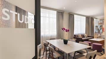 Una habitación de hotel moderna con zona de comedor, sofá y una mesa de centro.
