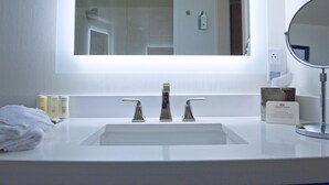 A bathroom with a white sink, three faucets, a large mirror, and toiletries on the counter. - Crowne Plaza: Philadelphia - King of Prussia by IHG (King of Prussia)