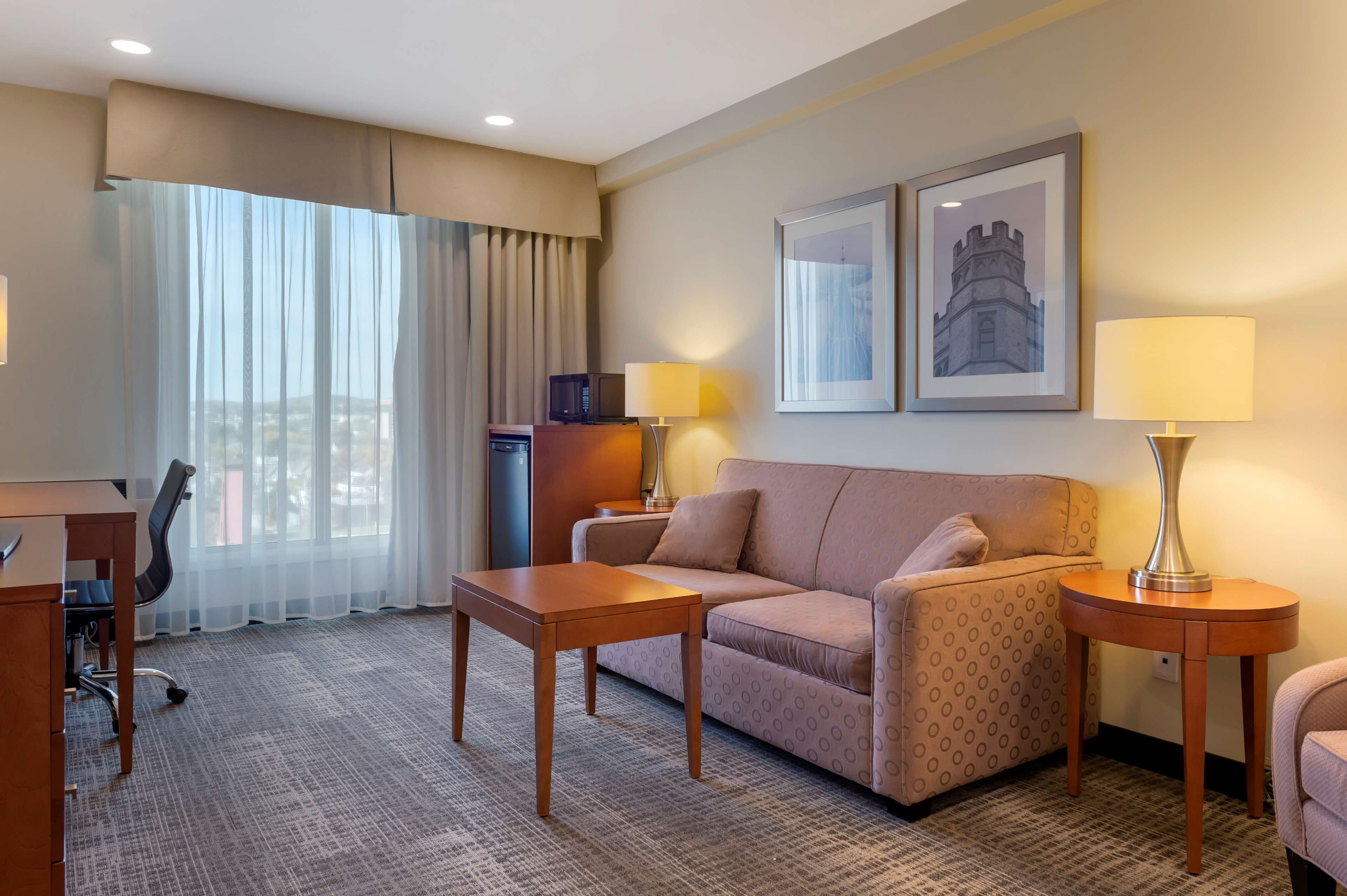Habitación de hotel con sofá, dos lámparas, escritorio y una silla.