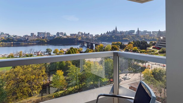 A balcony with a view of a cityscape, including a river, bridge, and buildings.