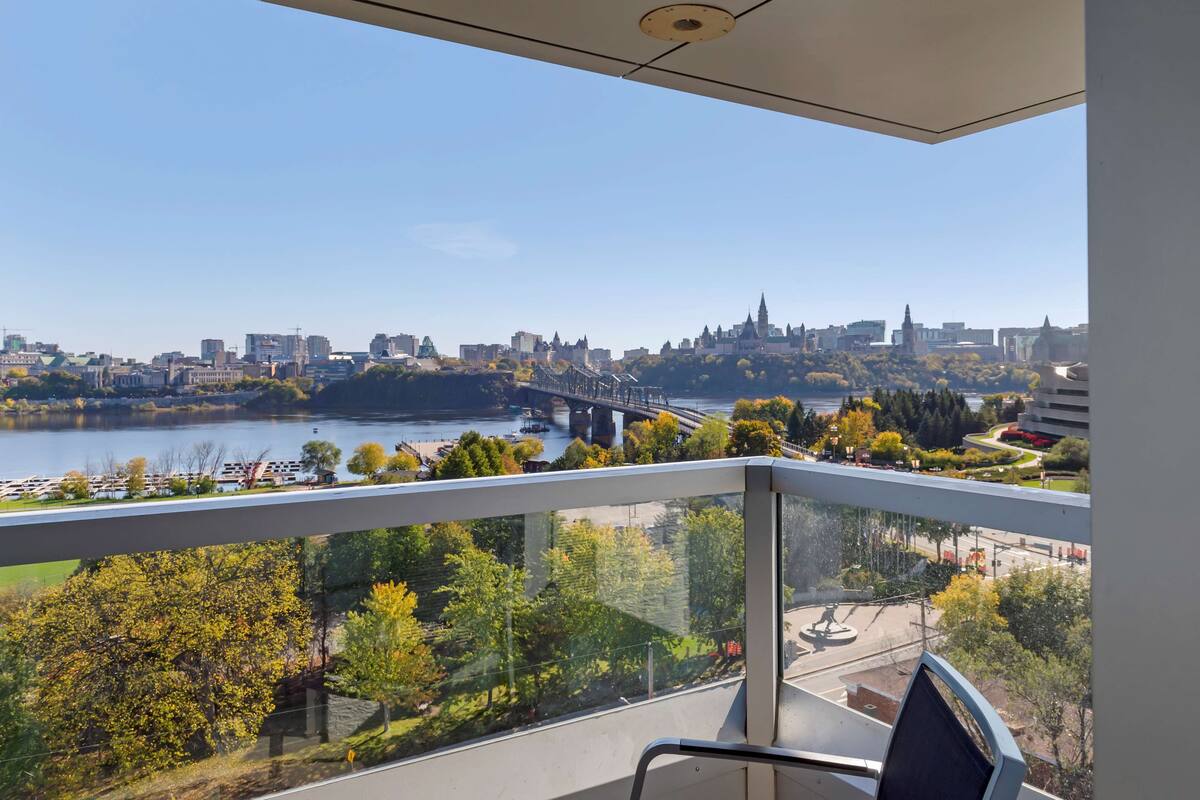 Un balcó amb vista a un paisatge urbà, incloent un riu, un pont i edificis.