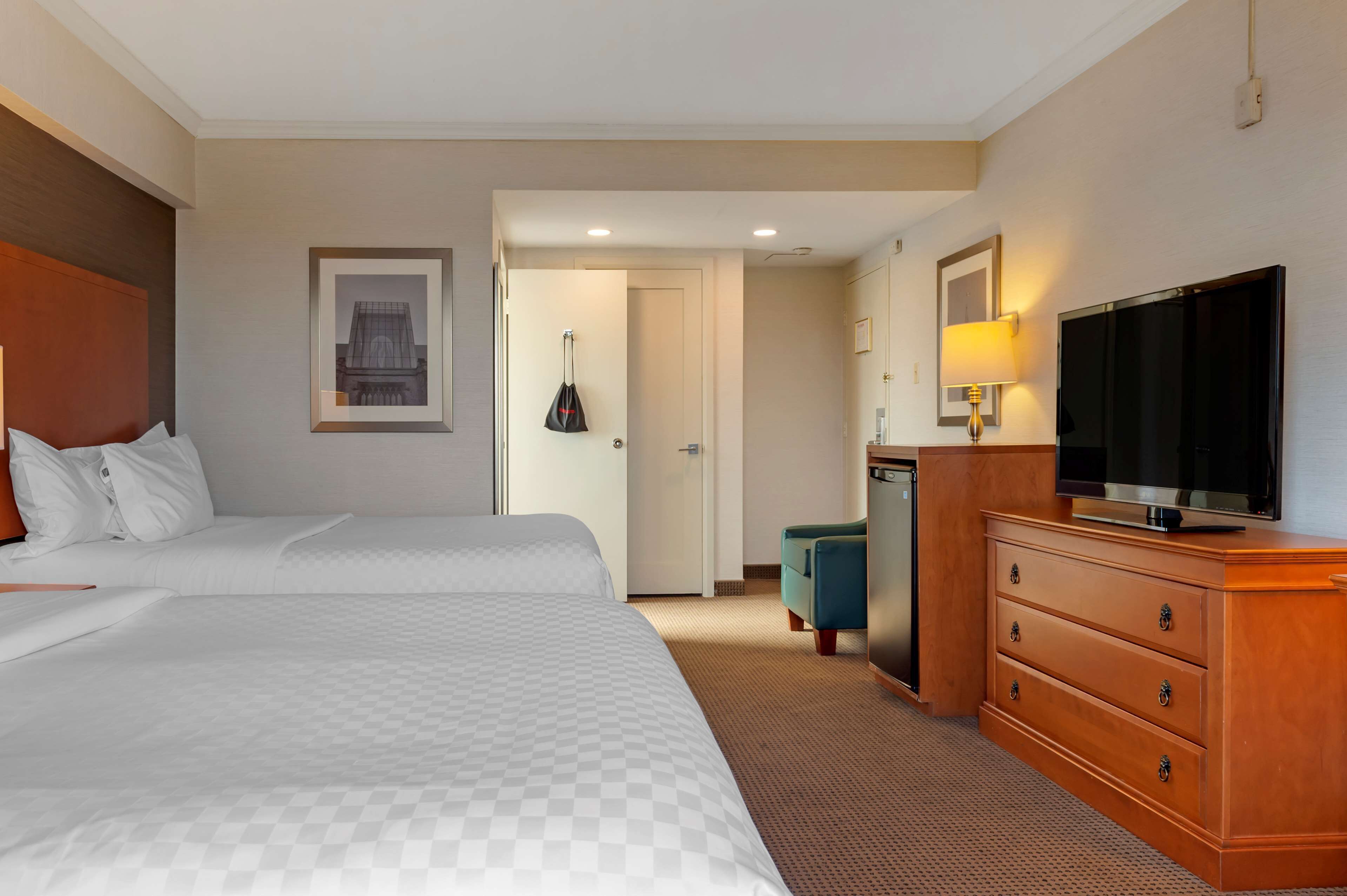 Una habitación de hotel con dos camas, televisión, cómoda y escritorio con lámpara.