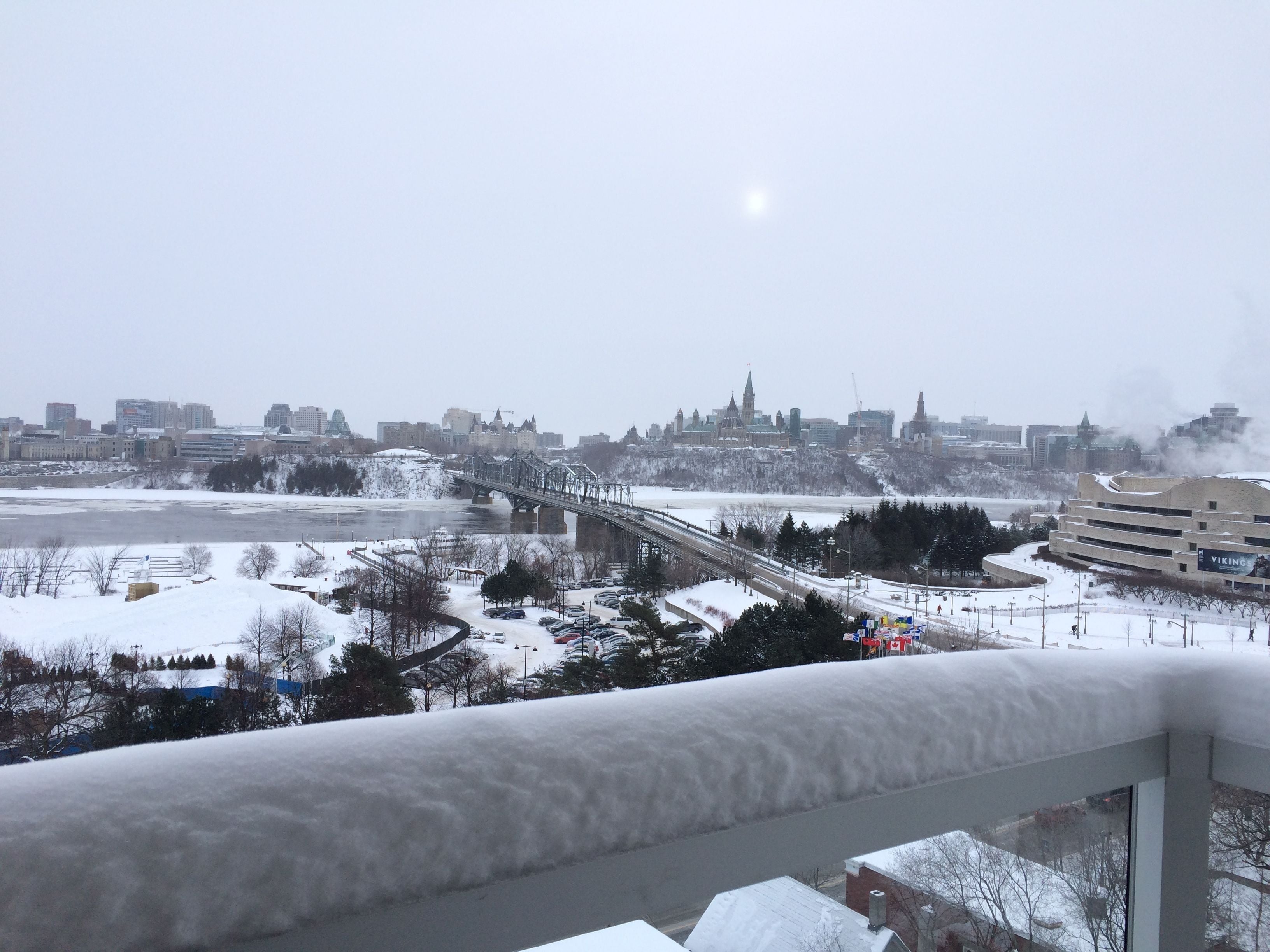 Eine verschneite Stadtlandschaft mit einer Brücke, Gebäuden und einem Fluss.