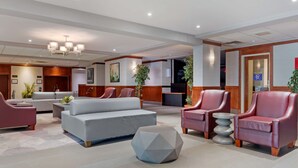 A modern lobby with a grey sofa, red armchairs, and a unique geometric coffee table.