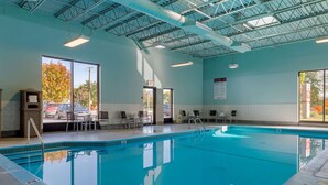 An indoor swimming pool with clear glass walls, a tiled floor, and a ceiling with visible structural beams.