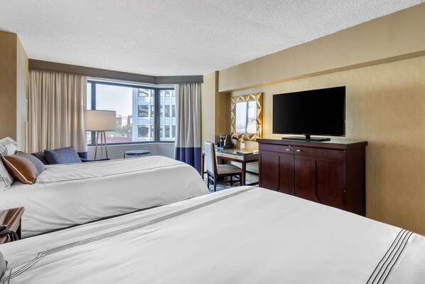 A hotel room with two beds, a desk, a TV, and a window with curtains. - Omni Richmond Hotel (Richmond)
