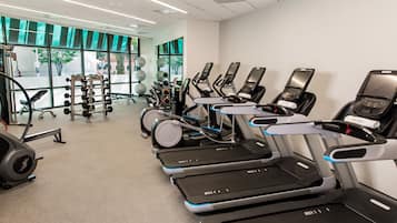 Un gimnasio con cintas de correr, bicicletas estáticas y máquinas de pesas.