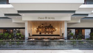 The exterior of Omni Hotel with a modern design, featuring a large seating area with tables and chairs, and a variety of potted plants around the perimeter. - Omni Richmond Hotel (Richmond)