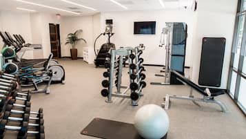 A gym with treadmills, dumbbells, a stationary bike, and a rowing machine.