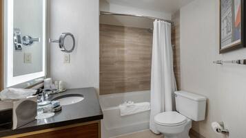 A modern bathroom with a sink, mirror, toilet, and shower.