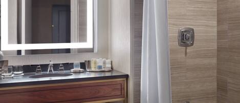 Un baño moderno con tocador, espejo, ducha y toallas.