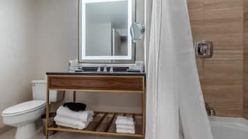 A modern bathroom with a wooden vanity, a large mirror, a toilet, and a shower area.