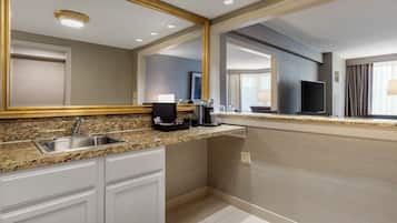 A modern kitchen with granite countertops, a stainless steel sink, and a large mirror above the counter.