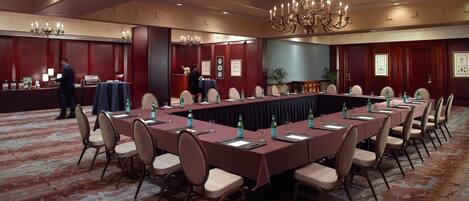 Un salón de conferencias con una larga mesa, sillas y un candelabro.