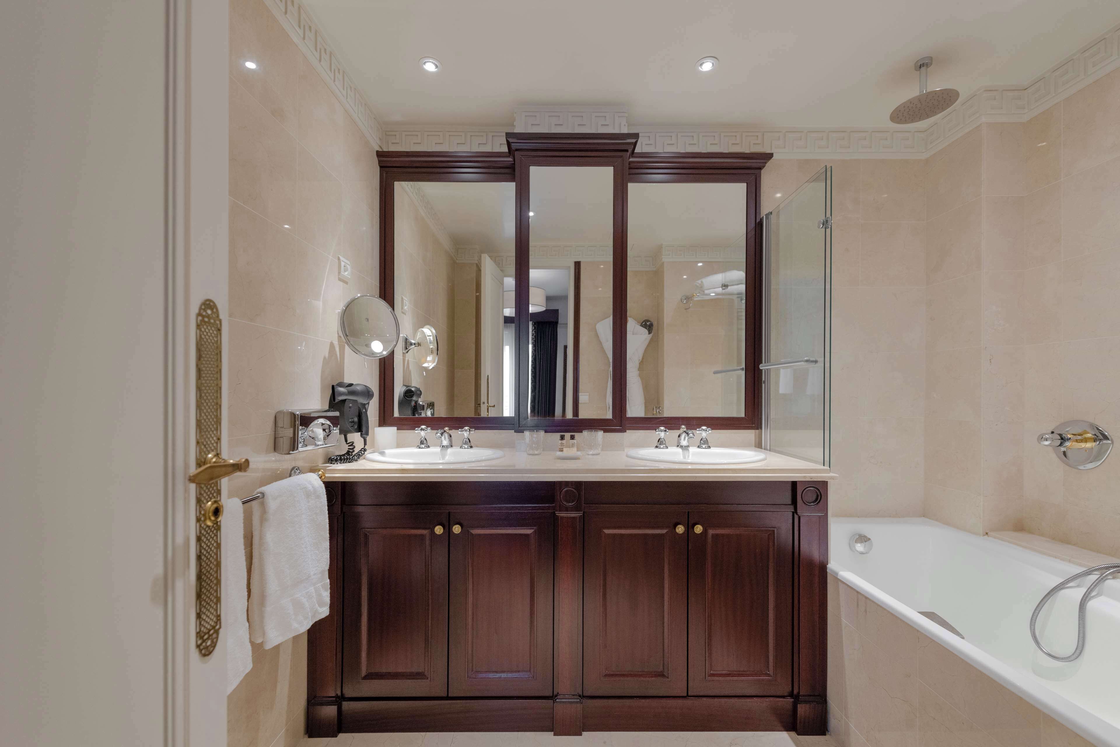 A modern bathroom with a double sink vanity, a large mirror, and a standalone bathtub.