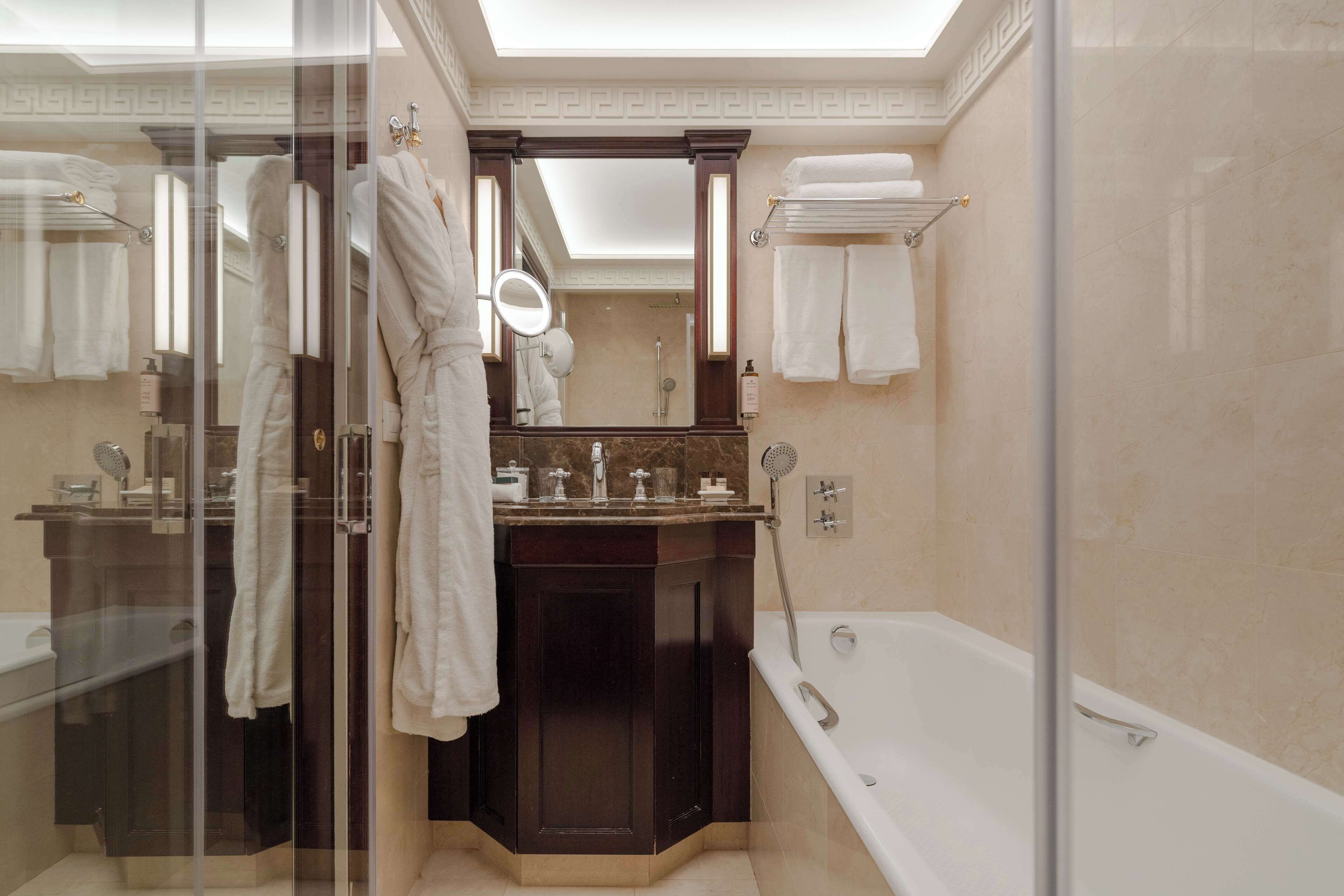 A modern bathroom with a glass-enclosed shower, a large mirror, and a bathtub.