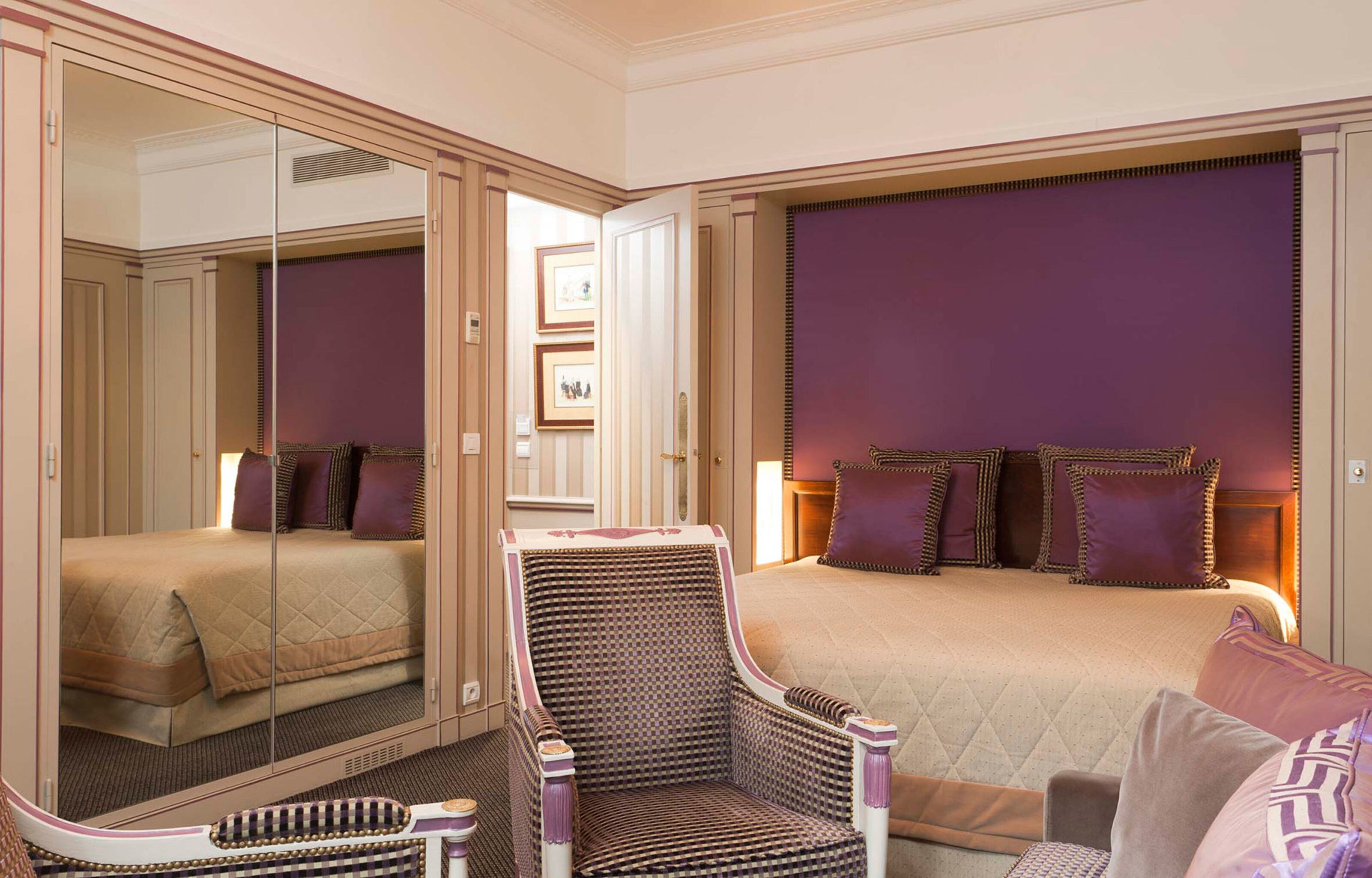 Une chambre d’hôtel avec un lit, une chaise, un miroir et une armoire.