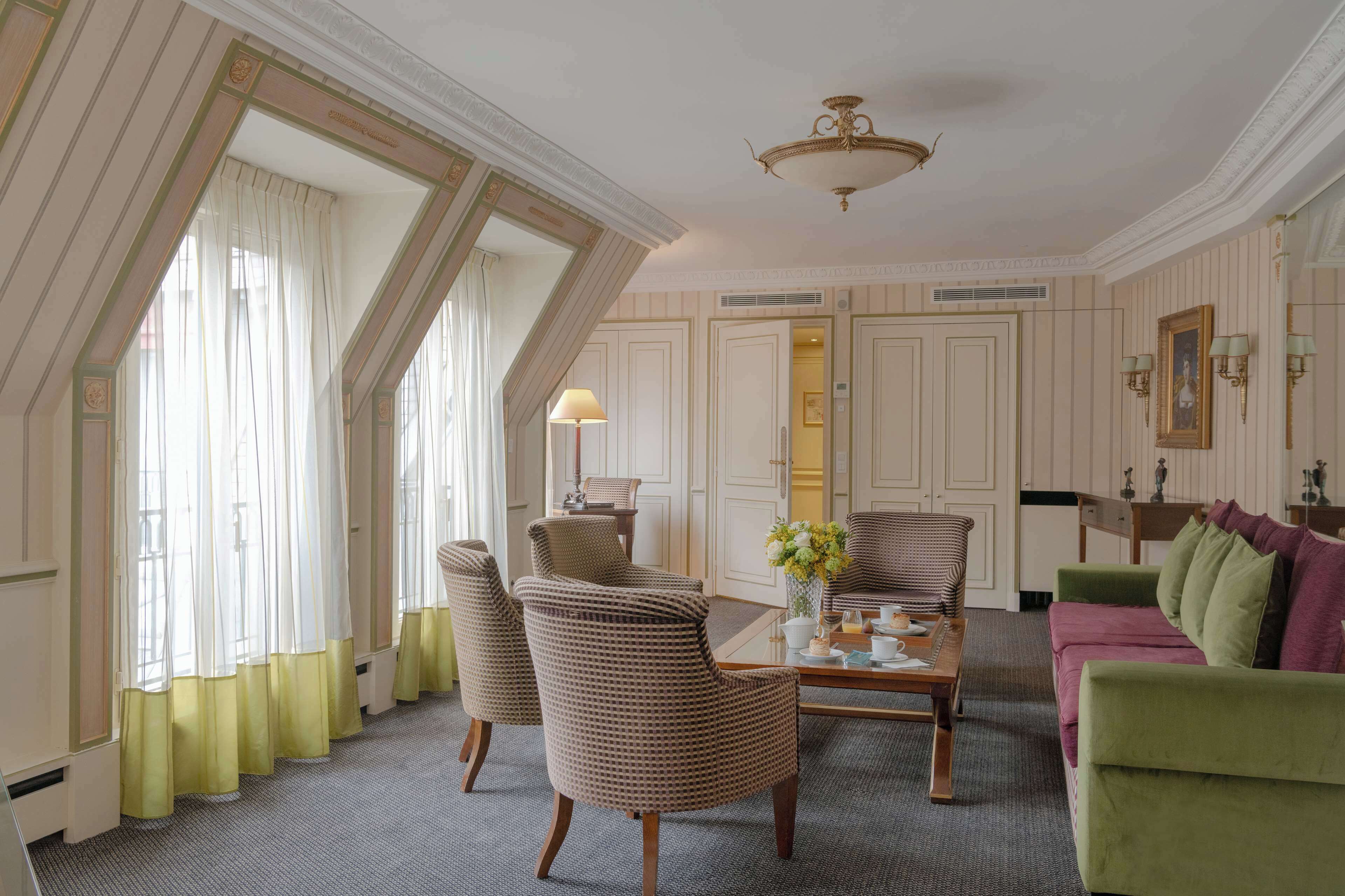 Ein gut beleuchteter Raum mit einem großen Fenster, einer Kristallleuchter und einem grünen Sofa.