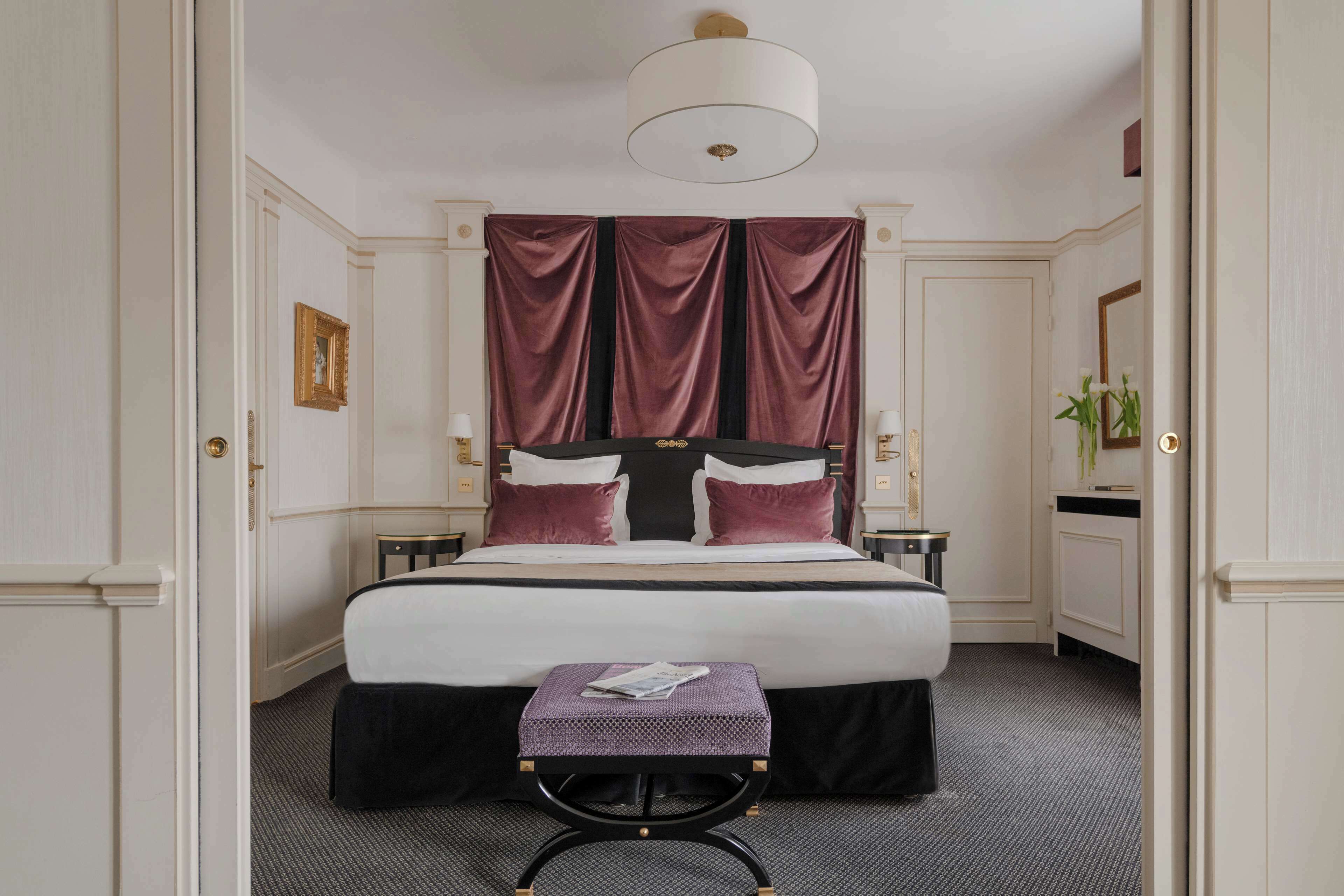 A hotel room with a large bed, a small table, and a mirror.