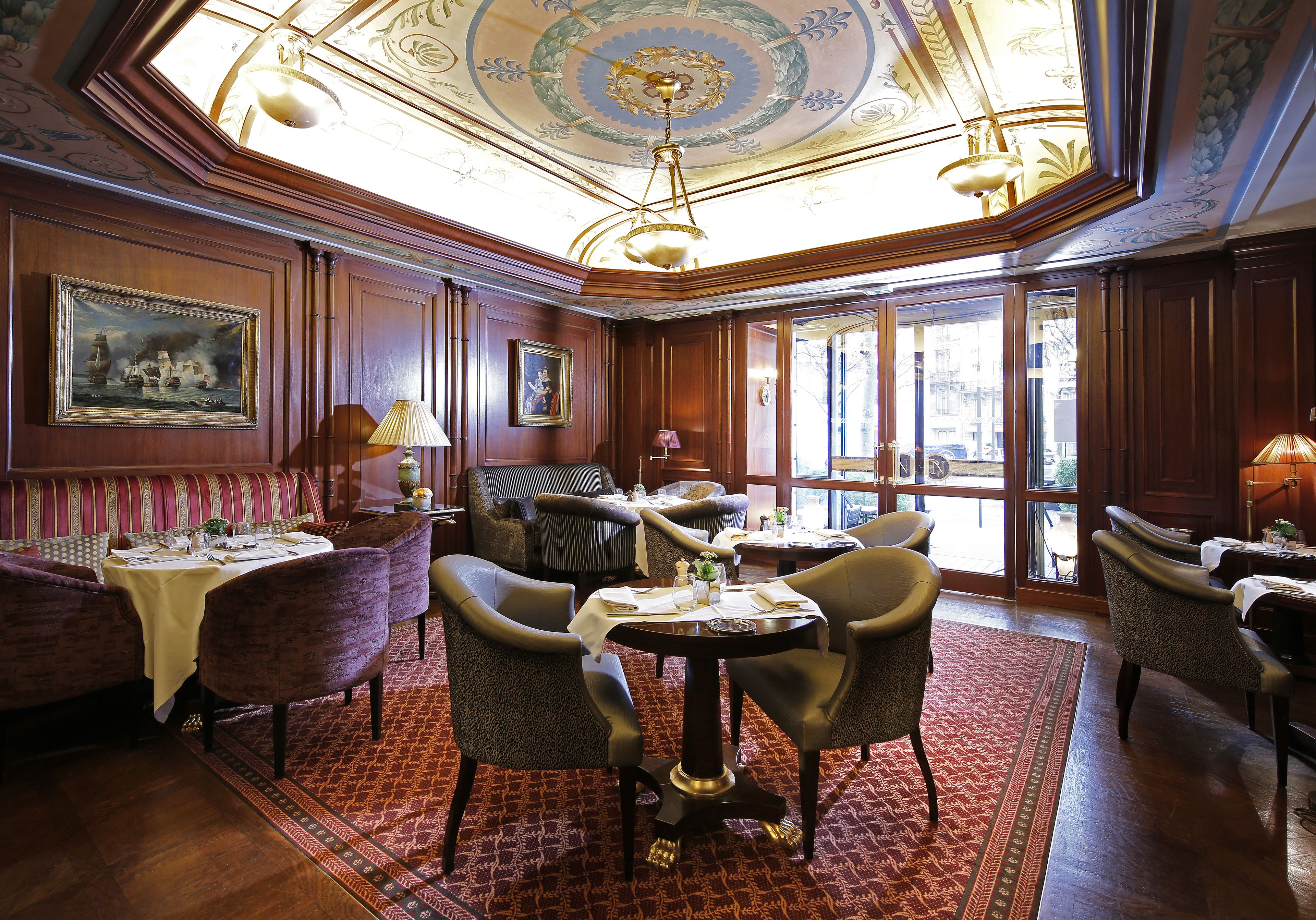 A dining area with wooden paneling, a chandelier, and a large window.