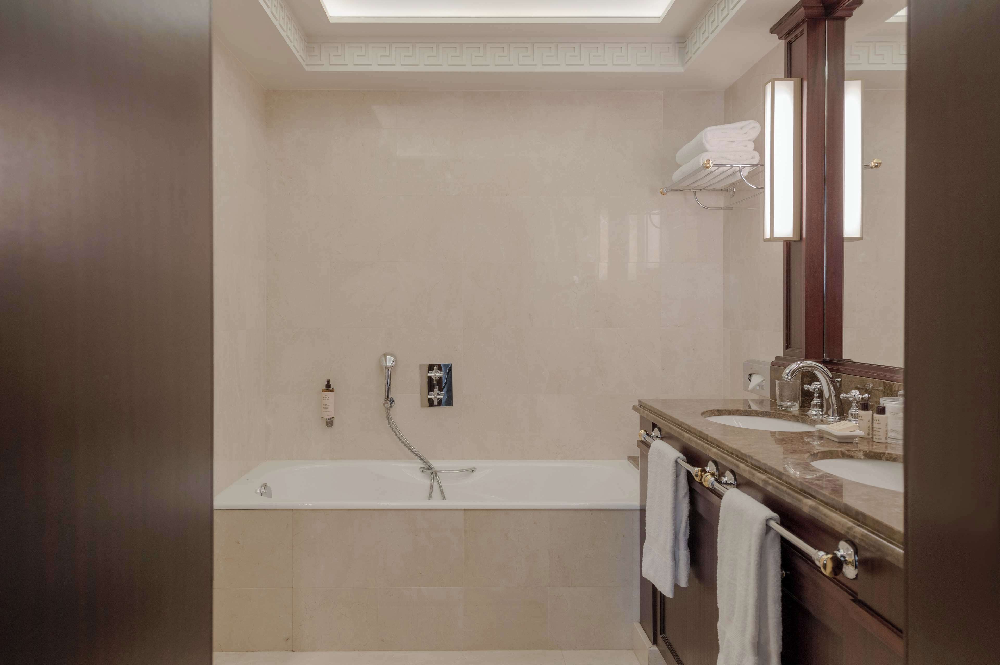 A modern bathroom with a bathtub, two sinks, and a large mirror.