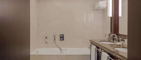 A modern bathroom with a bathtub, two sinks, and a large mirror.