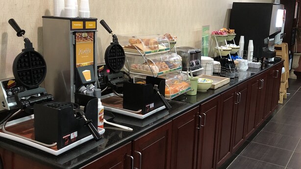 Un espace buffet proposant des gaufriers, un coin café et divers plats.