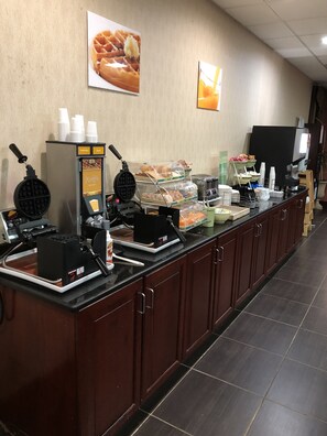 A buffet area with waffle makers, a coffee station, and various food items.